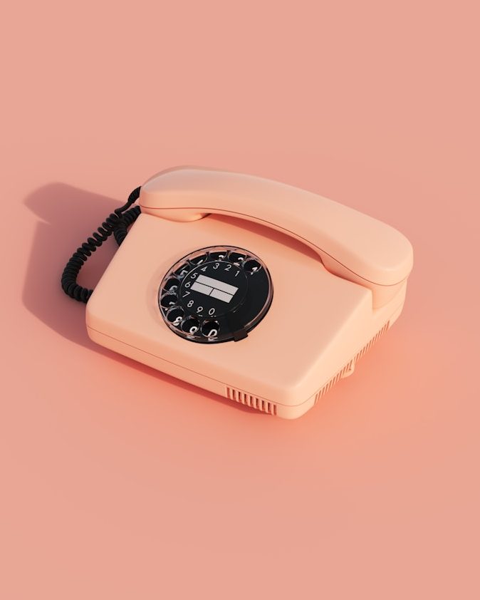 Rosa Vintage-Telefon mit einer Drehwähler-Tastatur auf pinkem Hintergrund.